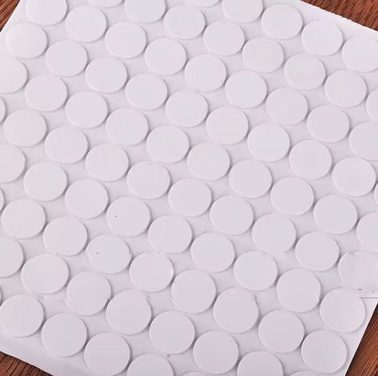 Een vel met honderden kleine, witte, ronde stickers, sommige met een schaduw.