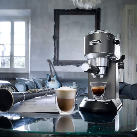 Grijze De'Longhi Dedica pistonmachine naast een glas espresso en een glas cappuccino.