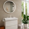 Moderne badkamer met witte wastafel met chromen kraan, spiegel met verlichting en grote plant.