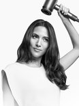 Vrouw met lang, steil haar gebruikt een zilvergrijze haardroger met diffuser.
