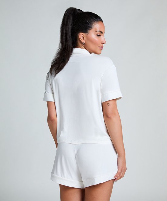 Model met staartje in een witte pyjamashort en bijpassend wit pyjamashirt met korte mouwen, gezien vanaf de achterkant.