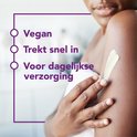 Vrouw met een witte handdoek, smeert crème op haar arm. Gezicht van een vrouw met parels. Tekst: Dagelijkse verzorging voor de eczeemgevoelige huid.
