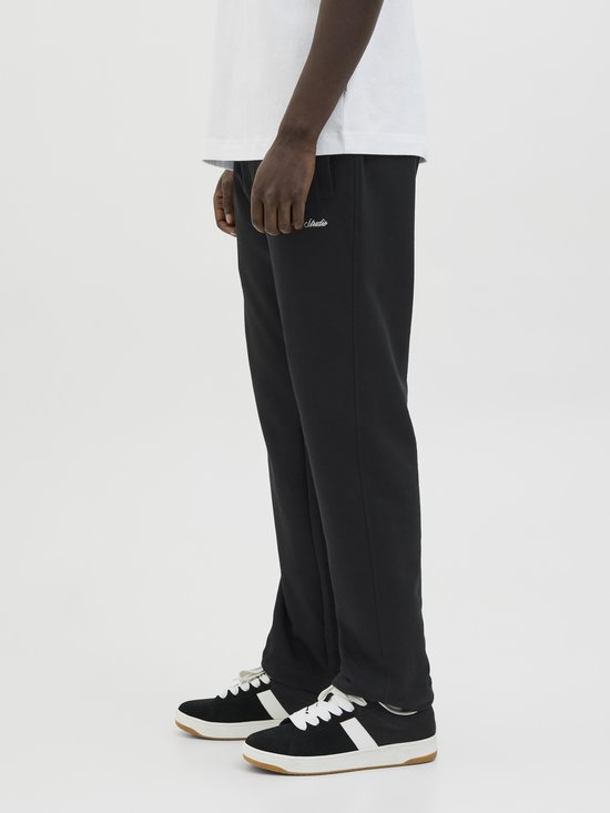 Zij-aanzicht van een zwarte joggingbroek met geborduurde tekst aan de zijkant.