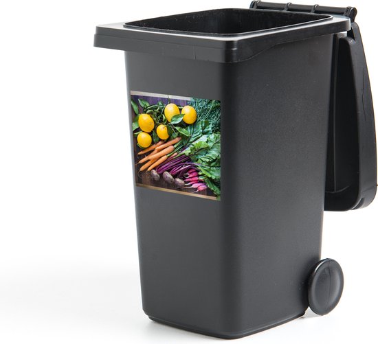 Poubelle grise avec autocollant de citrons, carottes et betteraves rouges.