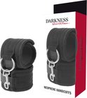 Zwarte neopreen manchetten naast de verpakking met de tekst 'DARKNESS'.