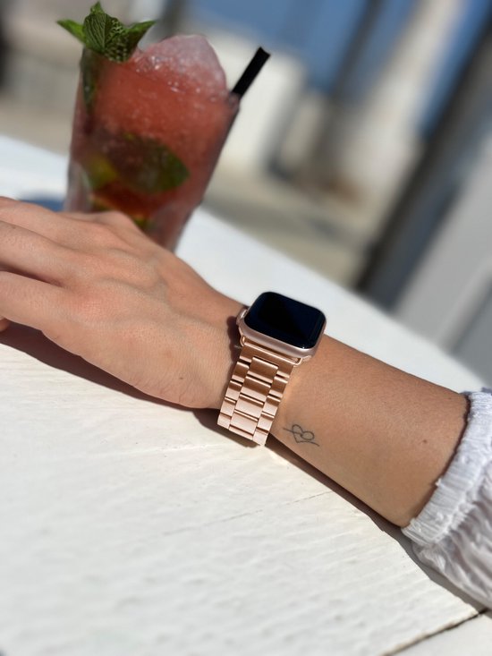 Rosegouden Apple Watch band aan een pols met een kleine hart tatoeage.