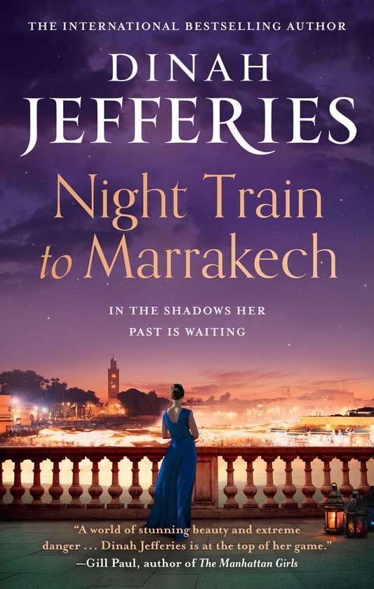Boekomslag met tekst 'Night Train to Marrakech' door Dinah Jefferies. Een vrouw in blauwe jurk kijkt uit over Marrakech bij zonsondergang.