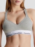 Model met grijze Calvin Klein bralette met diepe V-hals en witte band met logo.