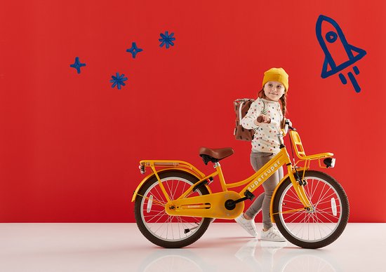 Meisje met gele muts en rugzak naast een gele fiets met bruin zadel en voorrekje.