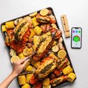 Gegrilde kreeftstaarten en maïskolven op een bakplaat, met citroenpartjes en een Meater thermometer en app.