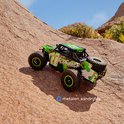 Groene en witte RC-auto "Acid Runner" met grote banden, rijdend op een rotsachtig terrein.