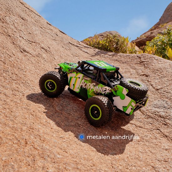 Groene en witte RC-auto "Acid Runner" met grote banden, rijdend op een rotsachtig terrein.