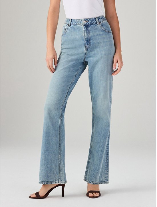 Model draagt een lichtblauwe jeans met wijde pijpen, een hoge taille en hakken.
