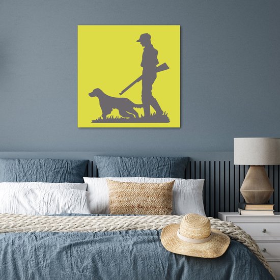 Poster met jager en hond op gele achtergrond, hangend boven een bed met blauwe en witte kussens.