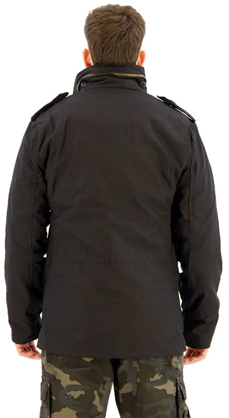 Zwarte herenjas, achterkant, met hoge kraag en epauletten. Gedragen met camouflage cargo broek.