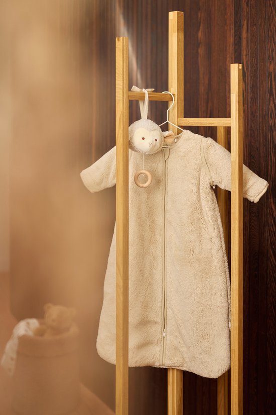 Beige teddy slaapzak met mouwen hangend aan een houten rek.