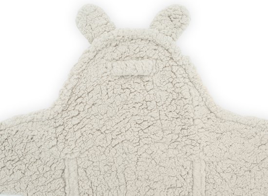 Close-up van een crème kleurige teddy wikkeldeken met konijnenoren en sluiting.