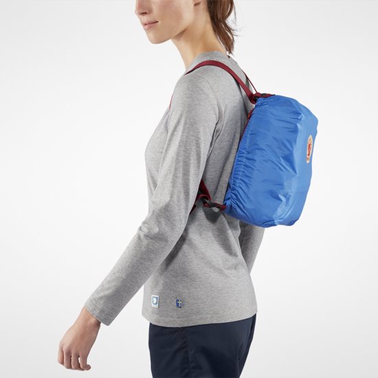 Vrouw met een blauwe opvouwbare rugzak op de rug gedragen aan dunne bandjes.