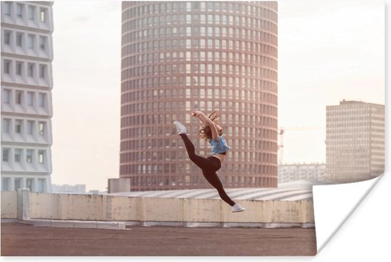 Dansende vrouw op het dak van een gebouw poster papier 90x60 cm - Foto print op Poster (wanddecoratie woonkamer / slaapkamer)