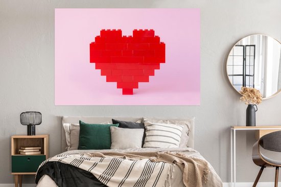 Rood hart van bouwblokken op een roze achtergrond, in een slaapkamer met een grijs bed.