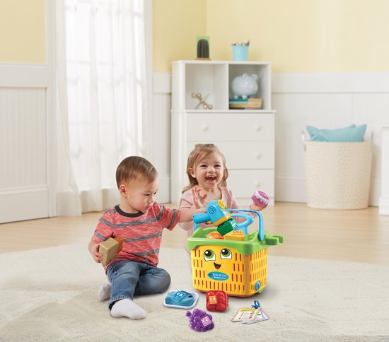 Twee jonge kinderen op een kleed, spelend met een felgekleurde speelgoedwinkelwagen.