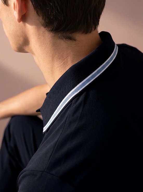 Donkerblauw poloshirt met contrasterende witte en blauwe strepen op de kraag.