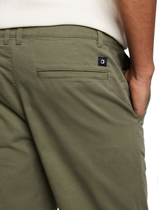 Olijfgroene chino met een zwarte patch op de achterzak.
