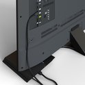 Achterkant van een donkergrijze televisie met aangesloten HDMI-kabel, verbonden met een zwarte gameconsole.