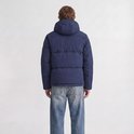 Man met rug naar de camera, draagt donkerblauwe pufferjack met capuchon.