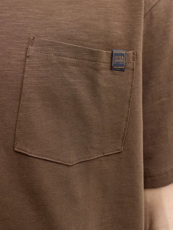 Detailopname van een bruine borstzak met blauw Jack & Jones label.