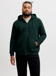 Model draagt een donkergroen JACK & JONES vest met rits, capuchon met trekkoord en een kangoeroezak.