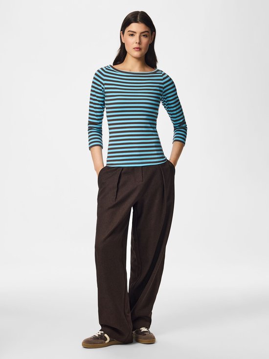 Volledig figuur van model in gestreept shirt, bruine pantalon en sneakers.