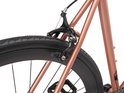 Koperkleurig fietsframe met zwarte velgen en banden. Close-up van de achterrem.