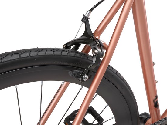 Koperkleurig fietsframe met zwarte velgen en banden. Close-up van de achterrem.