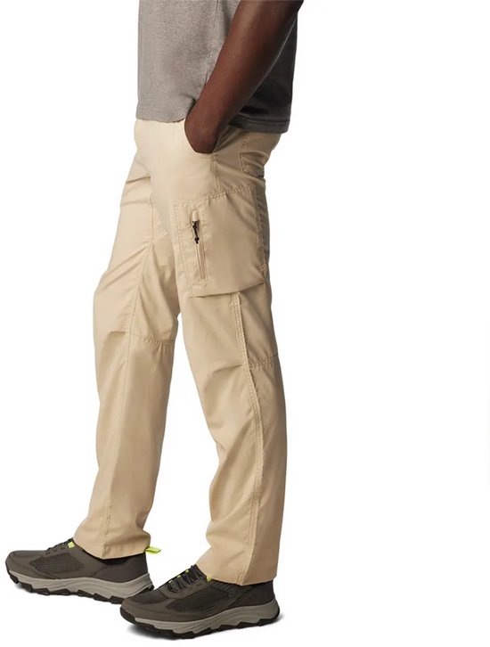 Zijaanzicht van een man in een beige cargo broek met opgestikte zakken, waarvan één met rits, en een grijze T-shirt.