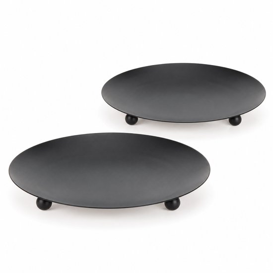 Twee ronde, zwarte metalen kaarsenplateaus op drie korte pootjes.