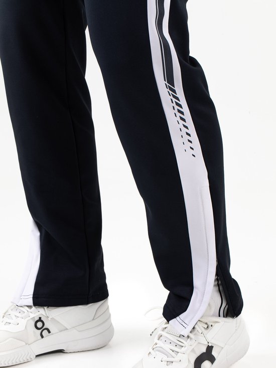 Close-up van de onderkant van een marineblauwe Sjeng Sports broek met witte zijstreep en enkelrits.