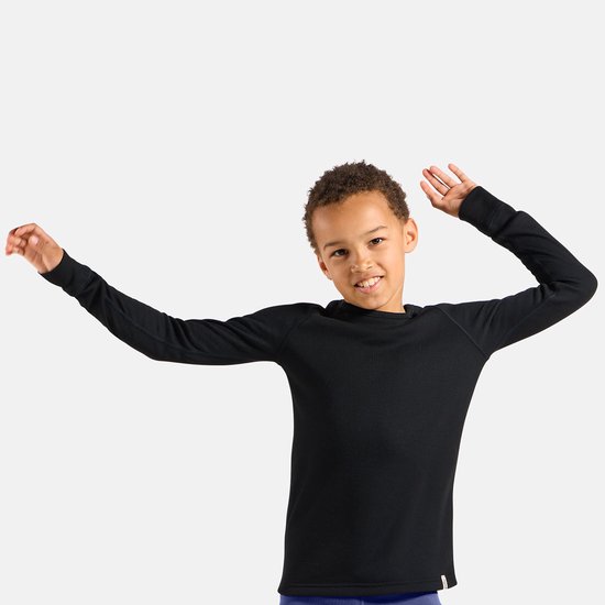 Kind met een glimlach, gekleed in een zwart ODLO thermoshirt met lange mouwen en ronde hals.