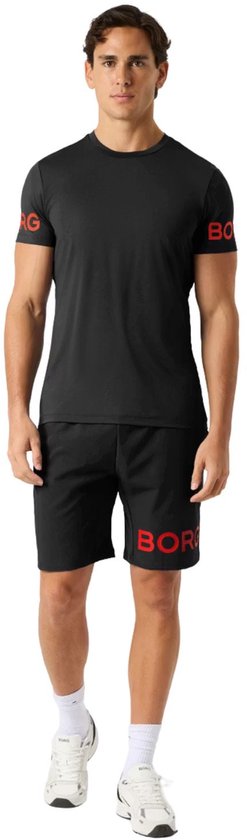 Man in zwart sportshirt met rode opdruk 'BORG' op mouwen en korte broek.
