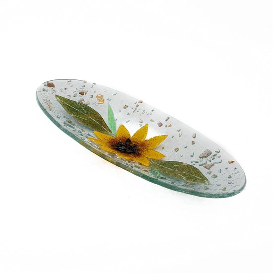Ovale glazen schaal versierd met een zonnebloem, groene bladeren en gekleurde glasfragmenten.