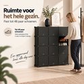 Persoon plaatst schoenen in een zwarte modulaire kast met 48 vakken in een licht interieur.