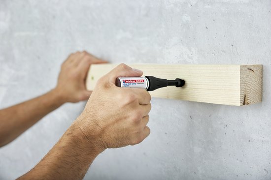 Hand gebruikt edding 8875 deep hole spray marker om een markering door een geboord gat in een houten balk aan te brengen.