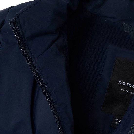 Detailopname van de binnenzijde van een donkerblauwe Name It jas met rits en merklabel.