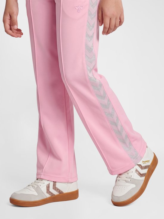 Roze joggingbroek met glinsterende zilveren chevrons op de zijkant, gedragen met witte sneakers.
