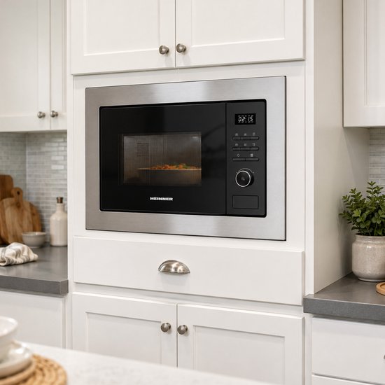 Heinner inbouwmagnetron is ingebouwd in witte keukenkastjes. De magnetron heeft een zilverkleurig frame en zwart display.