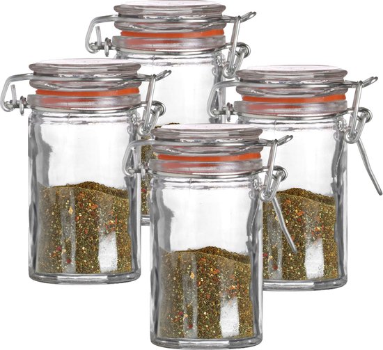 Quatre petits bocaux en verre, chacun rempli d'épices et avec joint orange et fermoir à levier argenté.
