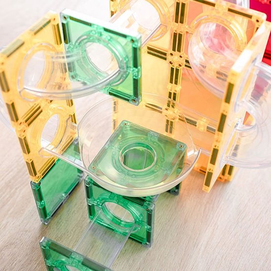 Doorzichtige buizen en spiraaltjes sluiten aan op vierkante en zeshoekige groene en gele magnetische tegels.