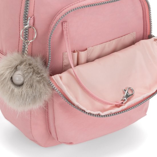 Gros plan d'un sac à dos rose avec poche ouverte, porte-stylos et pompon en peluche.