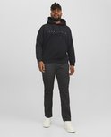 Man in volledig zwarte hoodie met 'JACK & JONES' opdruk en grijze cargo broek.
