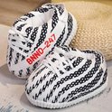 Zwart-witte sneaker-pantoffels met veters en rode BNND-247 tekst naast een rieten mand.